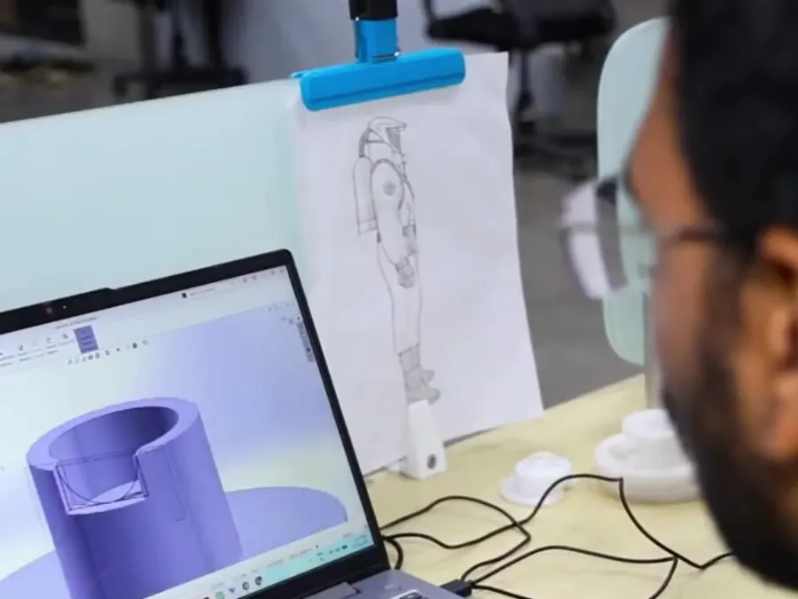 Engineer designing a suit fitting in CAD software on a laptop