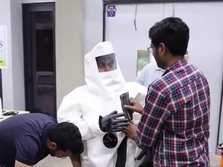 Two team members helping a person into the P Suits prototype